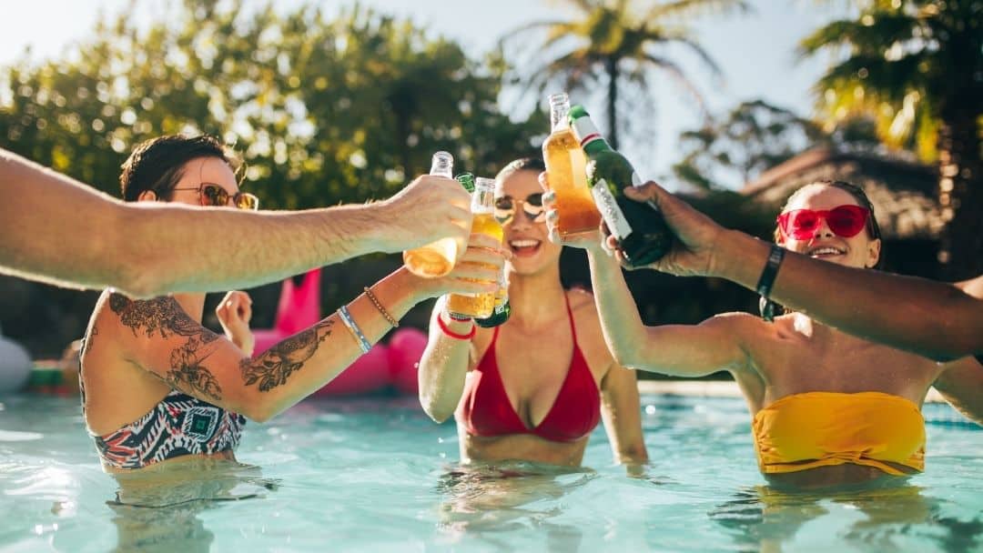 friends drinking mixed drinks in a pool