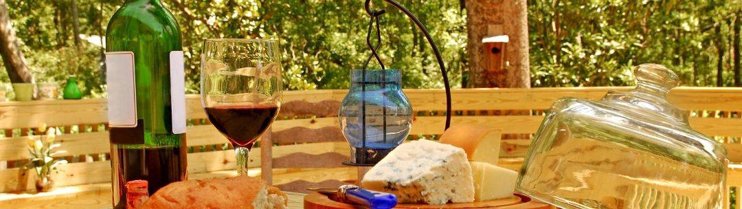 A nice spread of food on an outdoor table set on a wooden deck.